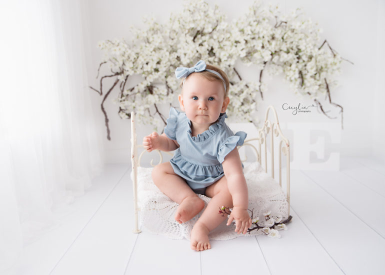 a small baby sititng on the bed having fun on the cecylia photosession