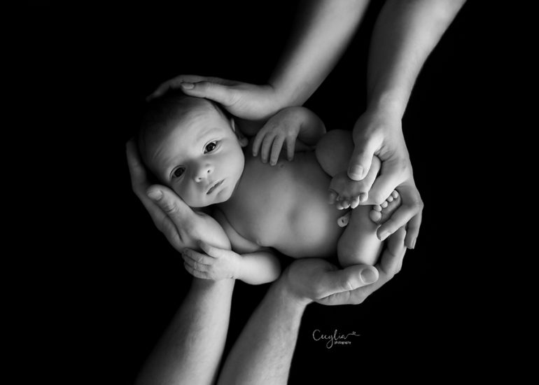 newborn baby on parents hands