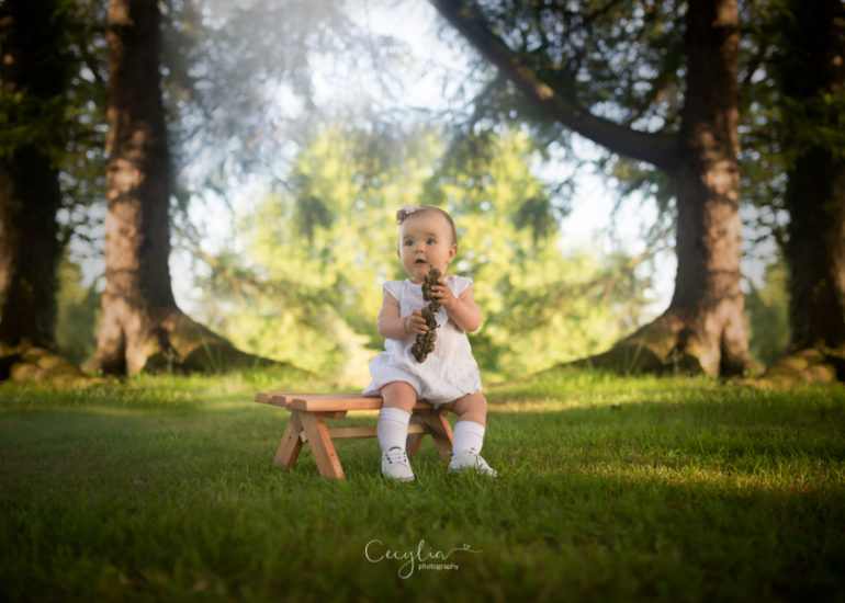 a baby girl on a small bench in park