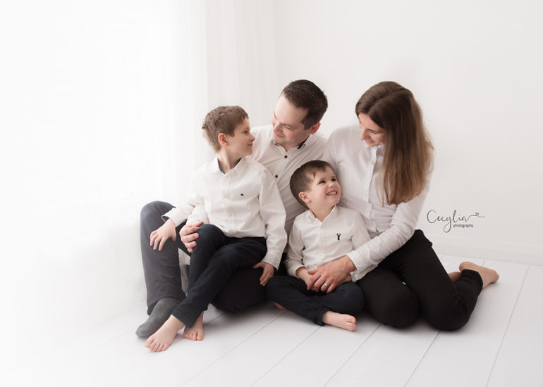 family of four in white clothes on the bed