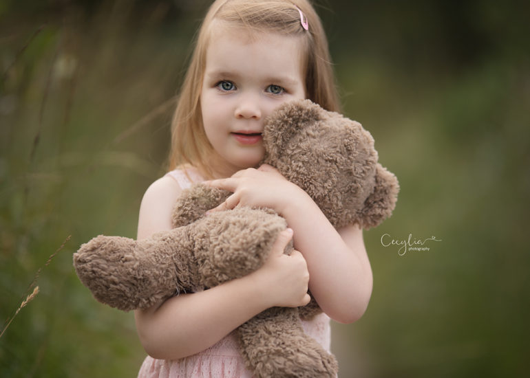 a girl holding a soft bear toy