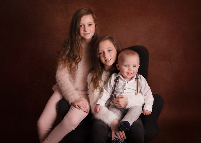a baby boy with two sisters in cecylia photography studio