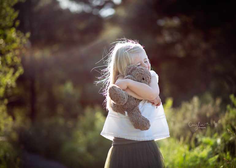 a baby holding a teddy bear in the park