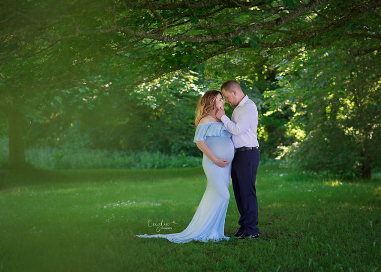 a couple expection a baby standing in the park