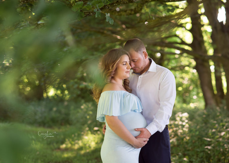 a couple expecting a baby posing together in the park