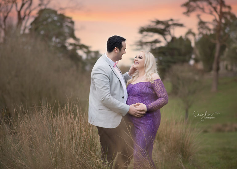 a couple expecting a baby holding their hands in the park