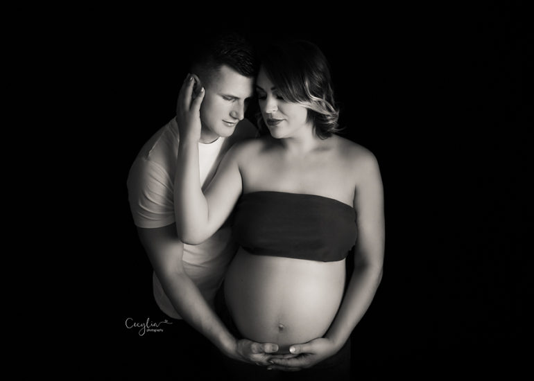 pregnant lady with partner posing on the black background