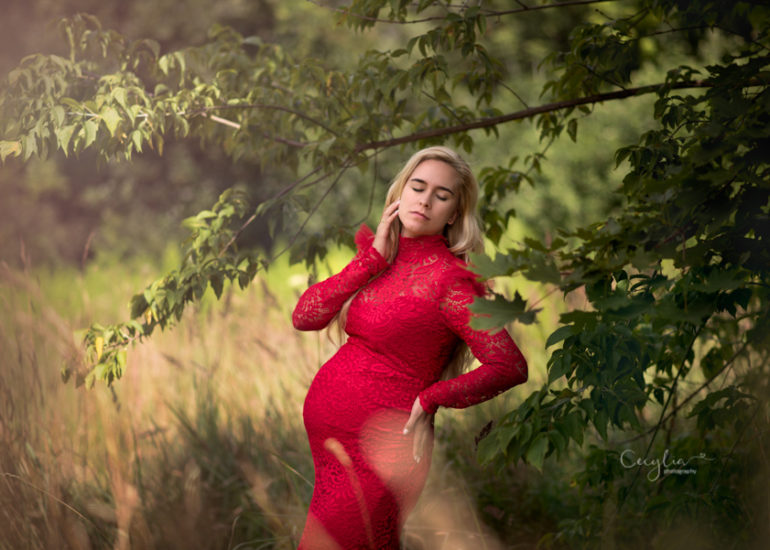 women in red dress posing on the maternity photo session in the park