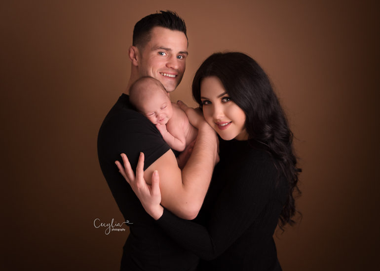 a couple in black clothes holding a baby