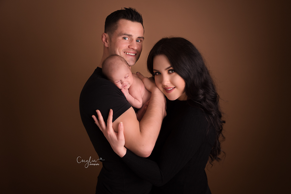 a couple in black clothes holding a baby