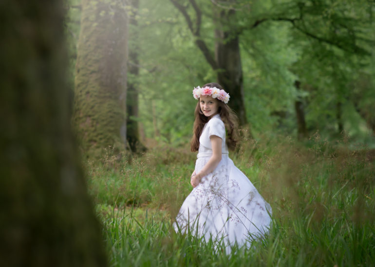 a girl in white dress in the park after her first holy communion