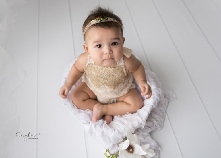 a baby girl sitting on the floor having sitters photo session