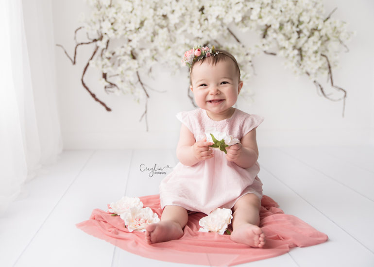smiling baby girl sitting on the floor in cecylia photography studio