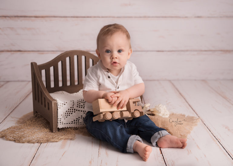 a baby sitting on the floor playing with wooden toy car