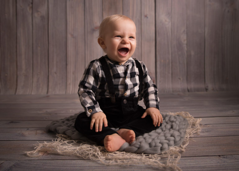 baby boy lauging to the camera on sitters photo session
