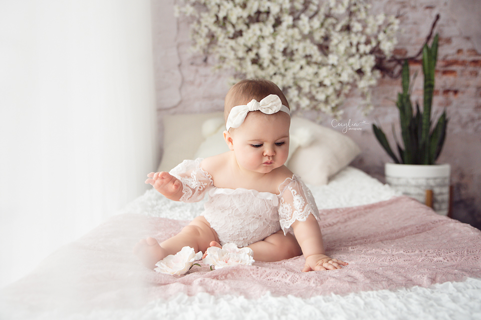a baby girl on the bed in white dress photo session