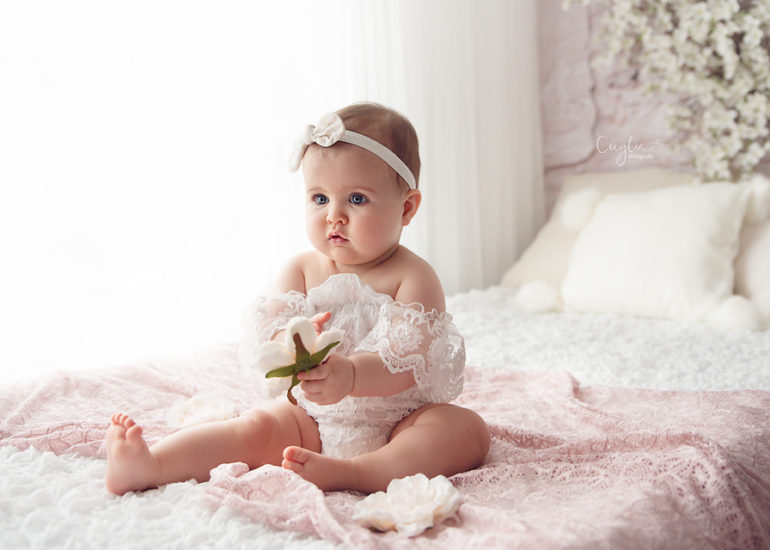 a baby on white dress on the sitters photo session