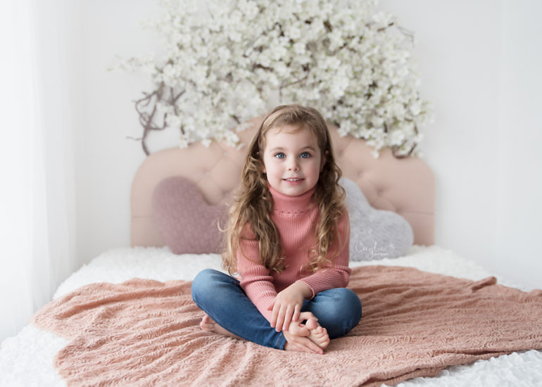 a girl sitting on the bed smiling to cecylia photography camera